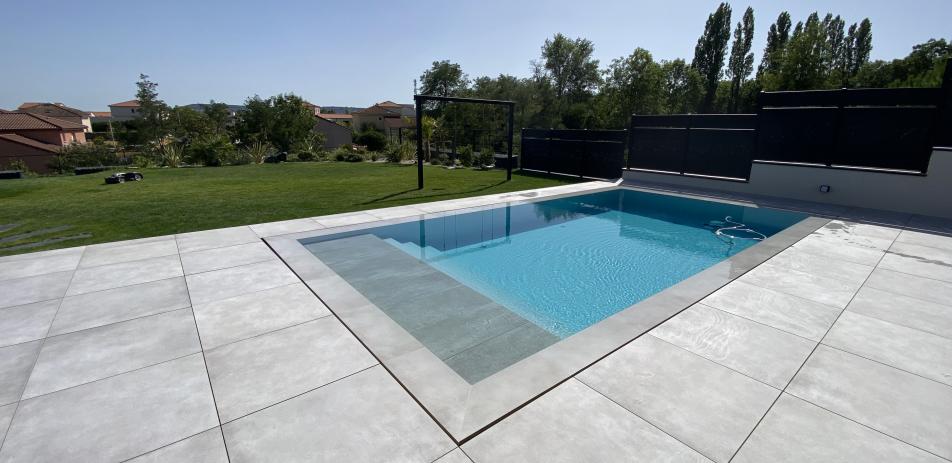 Piscine miroir entourée de gazon et terrasse carrelée